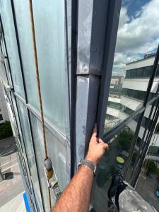 Vérification de la reprise d'étanchéité sur un montant de façade vitrée, chantier cordiste à Lyon