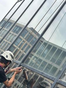 Cordiste appliquant le joint polyuréthane sur la façade vitrée d'un commerce à Lyon